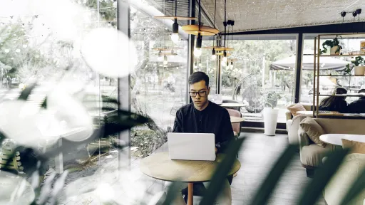 Smart looking young man sitting with a laptop in a cafe.